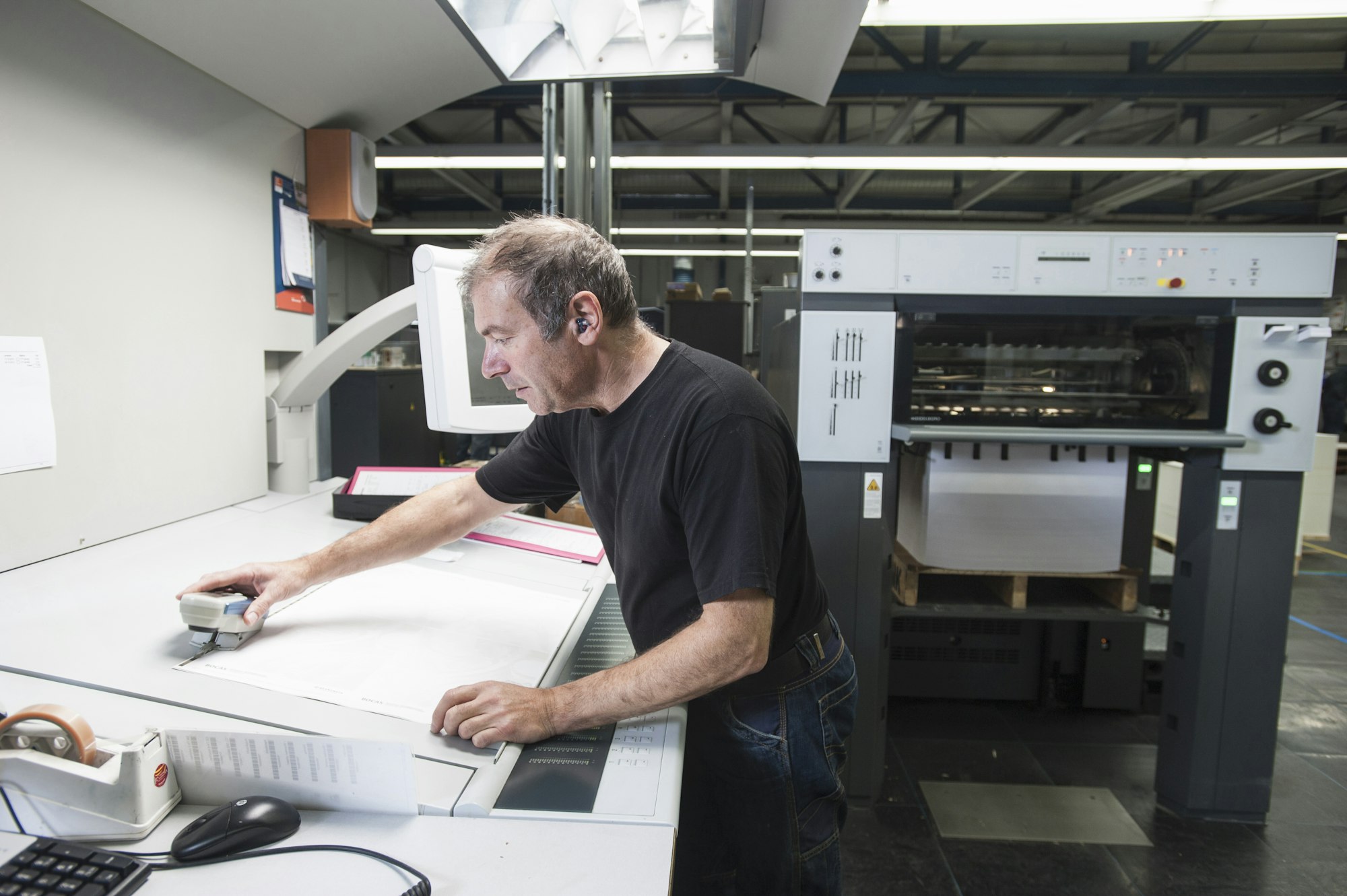 Worker preparing digital printing equipment in print workshop